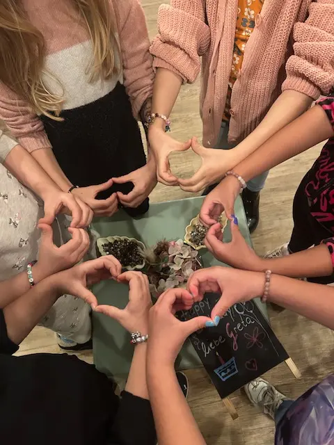 Kinderhände formen ein Herz aus Perlen